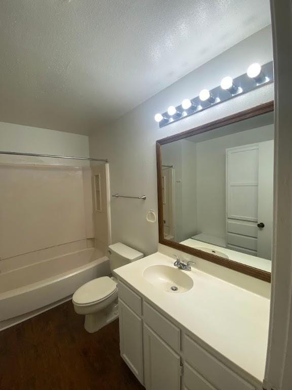 bathroom featuring toilet, tub / shower combination, a textured ceiling, vanity, and wood finished floors