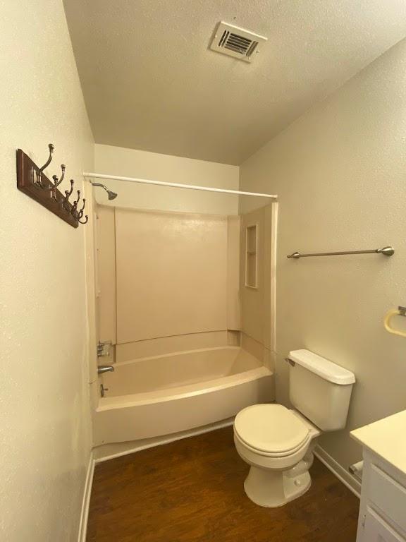 bathroom featuring a textured ceiling, wood finished floors, vanity, visible vents, and shower / washtub combination