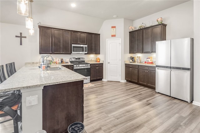 7906 Putter Pl, Navasota, TX 77868 - kitchen with stainless steel appliances, a sink, a peninsula, dark brown cabinetry, and decorative light fixtures