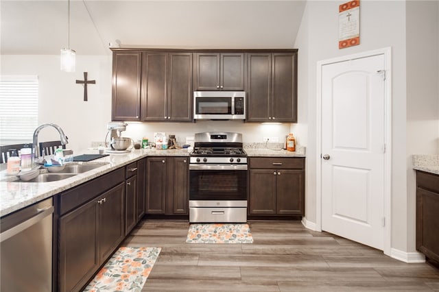 7906 Putter Pl, Navasota, TX 77868 - kitchen featuring appliances with stainless steel finishes, a sink, dark brown cabinets, vaulted ceiling, and light wood-style flooring