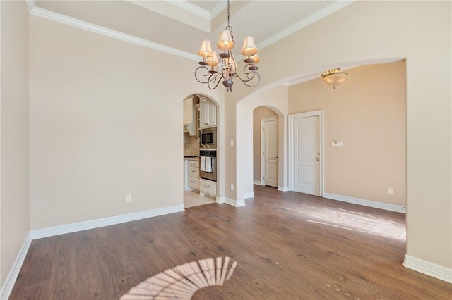 unfurnished dining area featuring arched walkways, an inviting chandelier, wood finished floors, and ornamental molding