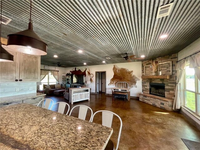 kitchen with plenty of natural light, ceiling fan, a fireplace, and a breakfast bar area