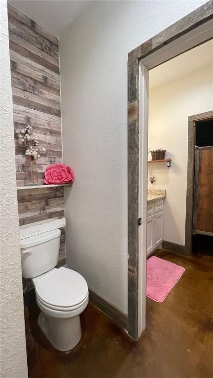 bathroom with concrete flooring, vanity, and toilet