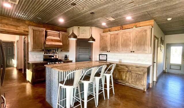 kitchen featuring backsplash, stainless steel range, a kitchen island, custom range hood, and a breakfast bar area