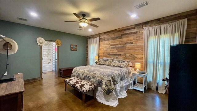 bedroom featuring ceiling fan, wooden walls, and ensuite bathroom