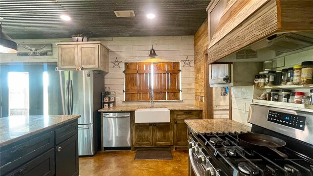 kitchen with custom exhaust hood, light stone countertops, sink, and appliances with stainless steel finishes