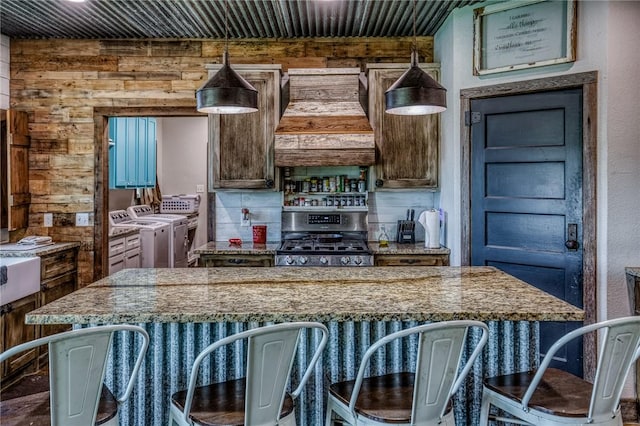 1850 Lcr 439, Groesbeck, TX 76667 - kitchen with stainless steel gas range, washing machine and dryer, wood walls, a breakfast bar, and custom range hood