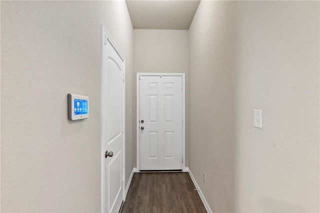 doorway with dark wood-style floors and baseboards