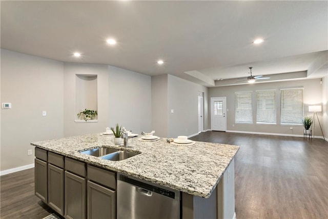 kitchen with light stone counters, open floor plan, a kitchen island with sink, a sink, and dishwasher