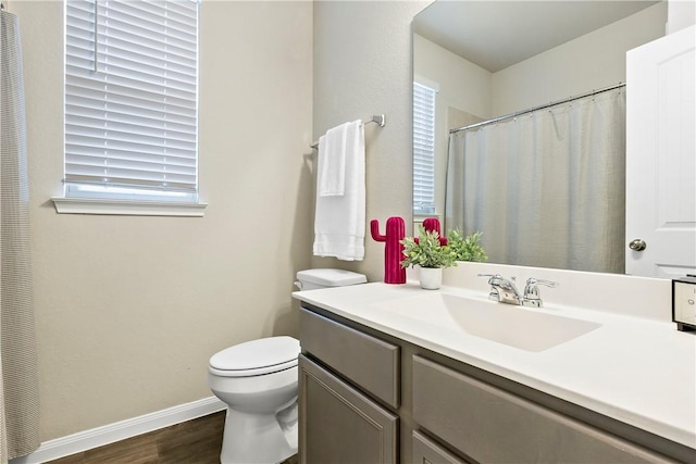 full bath featuring toilet, vanity, baseboards, and wood finished floors