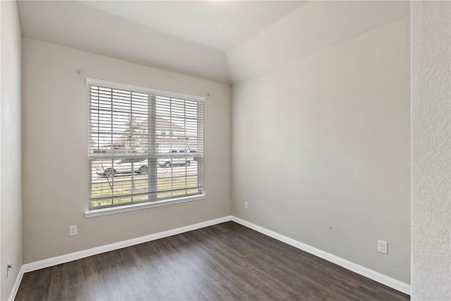 spare room featuring baseboards and dark wood finished floors