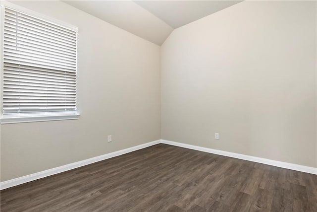 empty room with lofted ceiling, dark wood-style floors, and baseboards