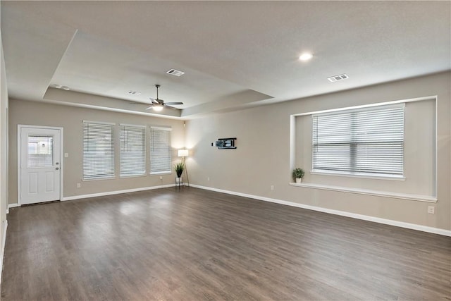 interior space featuring a raised ceiling, visible vents, and baseboards