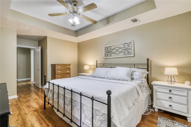 bedroom featuring hardwood / wood-style flooring, ceiling fan, and a tray ceiling