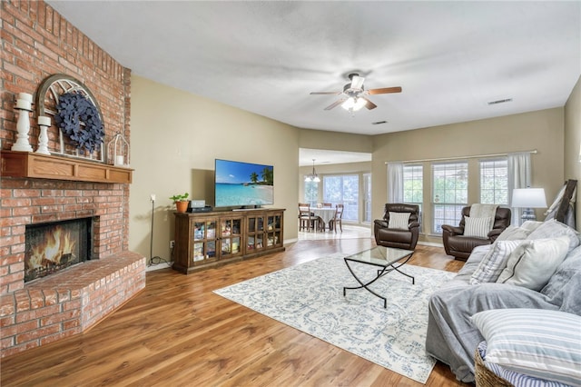 living room featuring hardwood / wood-style floors, a brick fireplace, and ceiling fan