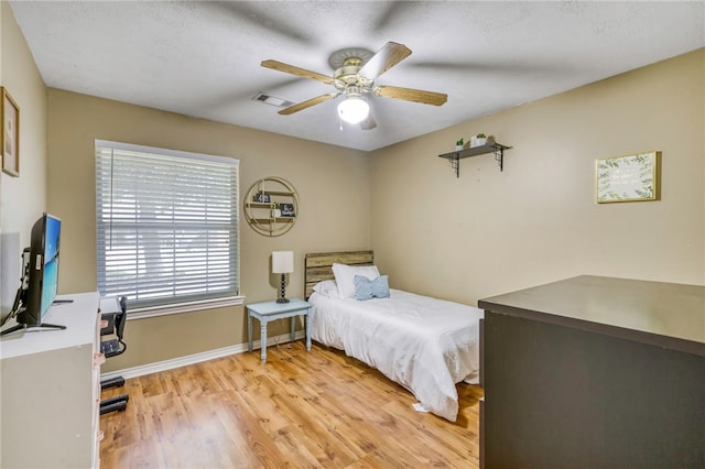 bedroom with ceiling fan, a textured ceiling, and light hardwood / wood-style flooring