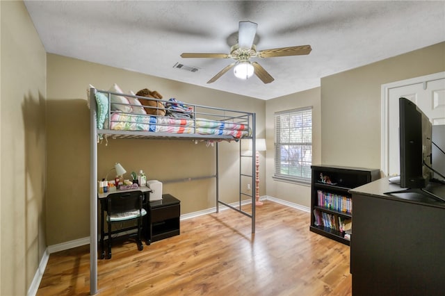 bedroom with ceiling fan, light hardwood / wood-style flooring, and a textured ceiling