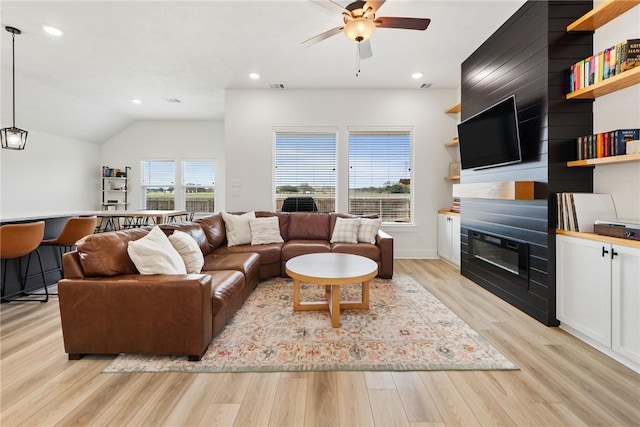 living room featuring ceiling fan, lofted ceiling, and light wood-type flooring