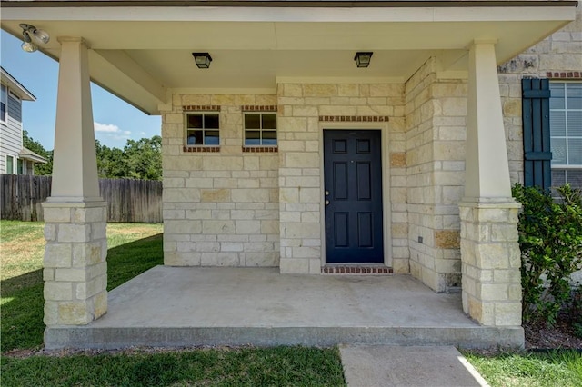 entrance to property with stone siding and fence