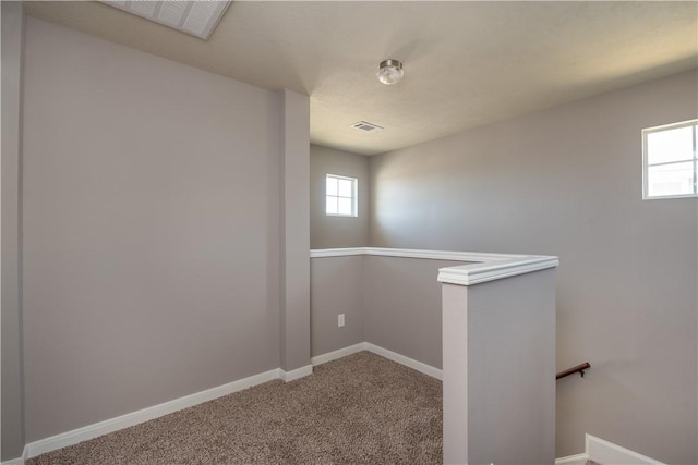 interior space featuring carpet, plenty of natural light, baseboards, and an upstairs landing