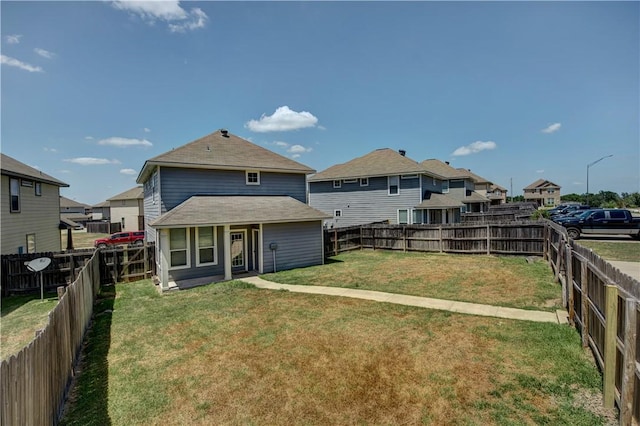 rear view of property featuring a residential view, a fenced backyard, and a lawn