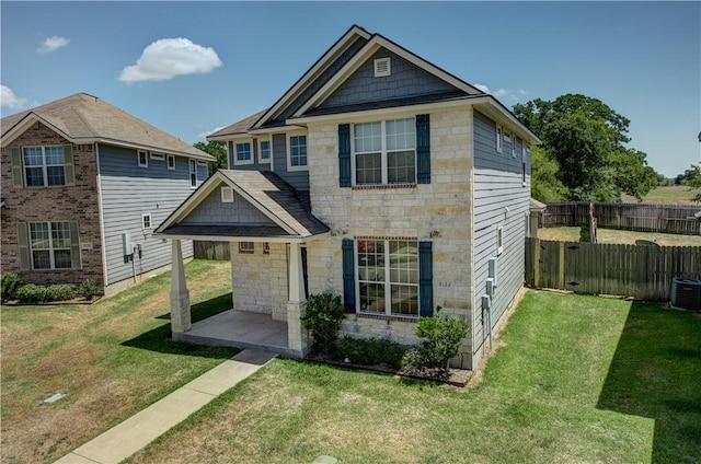 view of front facade featuring stone siding, a patio area, fence, and a front lawn