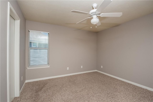 carpeted spare room featuring a ceiling fan and baseboards