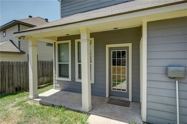 doorway to property with a shingled roof and fence