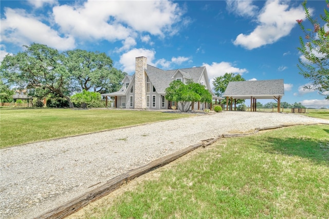 view of front of house with driveway, a chimney, a front lawn, and a carport