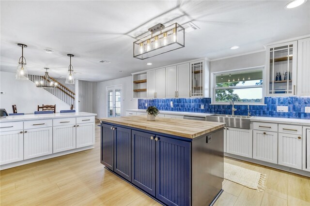 kitchen featuring a wealth of natural light, wooden counters, white cabinets, and a sink