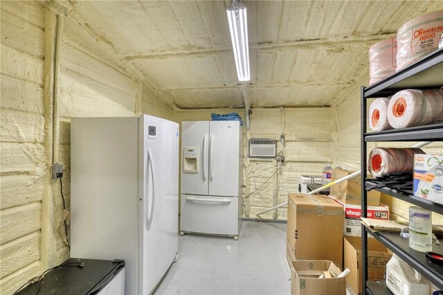 kitchen with white refrigerator with ice dispenser, concrete floors, a wall unit AC, and freestanding refrigerator