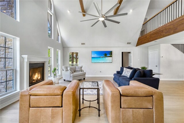 living room with baseboards, high vaulted ceiling, ceiling fan, and light wood-type flooring
