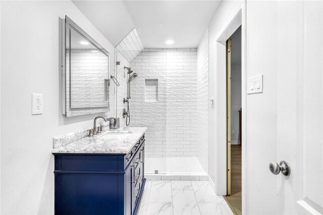 bathroom featuring a tile shower, recessed lighting, marble finish floor, and vanity