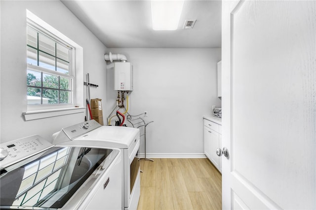 laundry room featuring cabinet space, tankless water heater, separate washer and dryer, visible vents, and light wood-style flooring