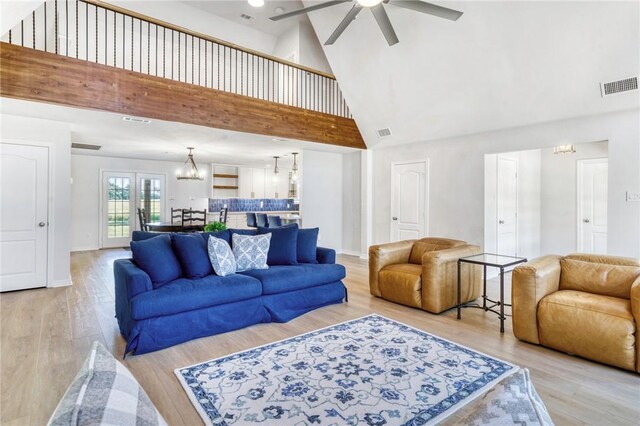 living room featuring visible vents, light wood-style flooring, high vaulted ceiling, and ceiling fan with notable chandelier