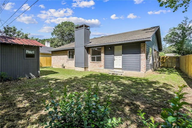 rear view of property featuring a shed and a yard