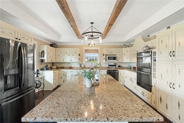 1858 Valley View Dr, Anderson, TX 77830 - kitchen with black appliances, a center island, cream cabinetry, light stone counters, and beam ceiling