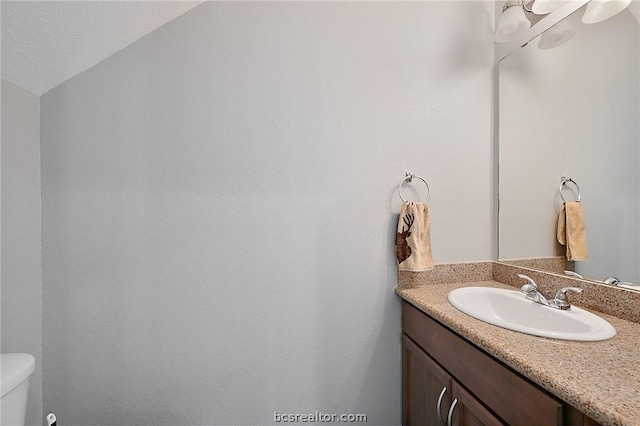 bathroom with vanity, toilet, and lofted ceiling