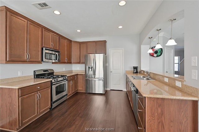 kitchen featuring sink, dark hardwood / wood-style floors, appliances with stainless steel finishes, decorative light fixtures, and kitchen peninsula