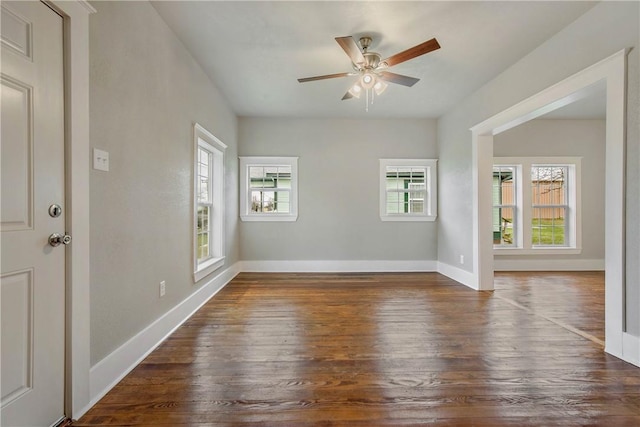 unfurnished room featuring ceiling fan, dark wood-type flooring, and baseboards