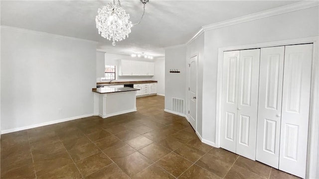 kitchen with white cabinets, a notable chandelier, ornamental molding, and hanging light fixtures