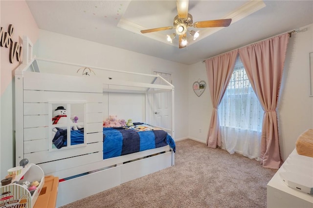 carpeted bedroom featuring a tray ceiling and ceiling fan