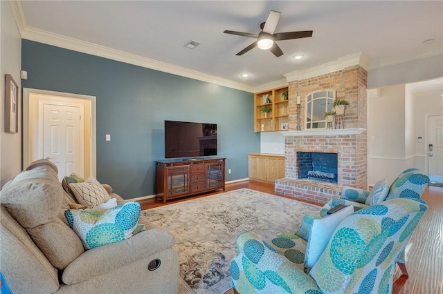 living room with ceiling fan, crown molding, hardwood / wood-style floors, and a brick fireplace