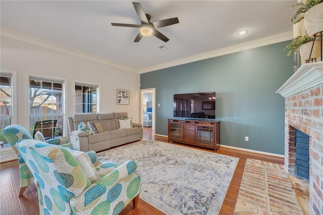 living room featuring hardwood / wood-style flooring, a brick fireplace, ceiling fan, and ornamental molding