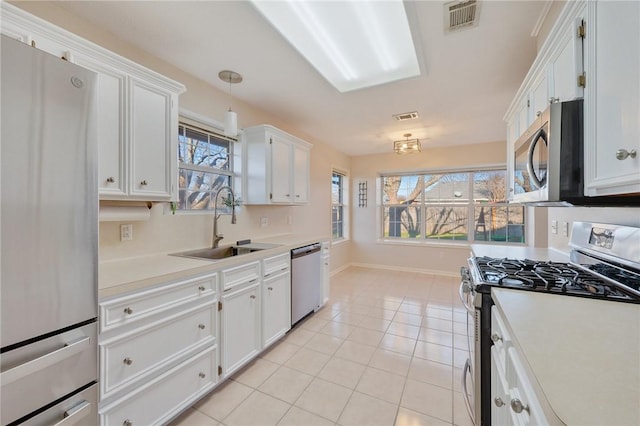 kitchen with stainless steel appliances, sink, light tile patterned floors, decorative light fixtures, and white cabinetry