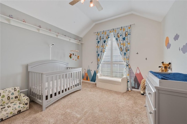 carpeted bedroom with ceiling fan, vaulted ceiling, and a nursery area