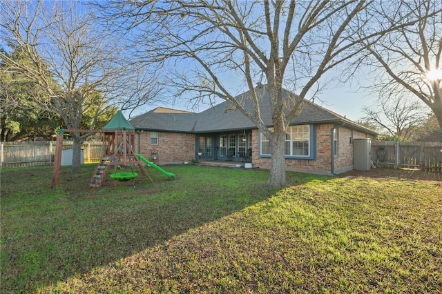 back of property featuring a yard and a playground