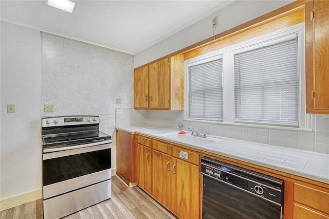 kitchen with sink, tile counters, black dishwasher, light hardwood / wood-style flooring, and stainless steel electric range