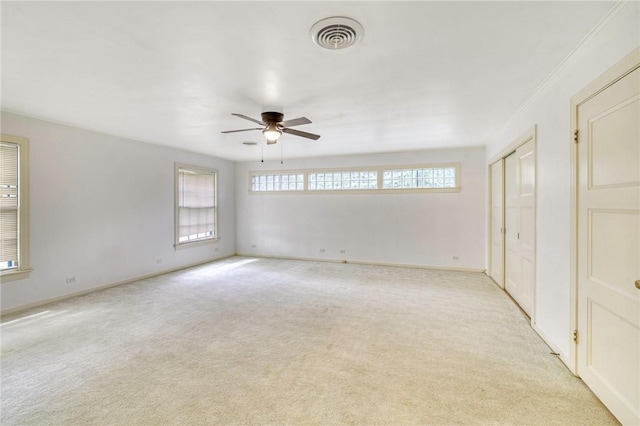 unfurnished room with ceiling fan, a healthy amount of sunlight, light colored carpet, and crown molding