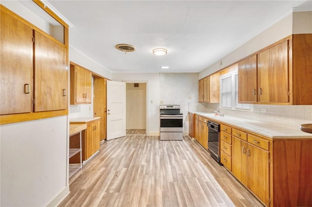 kitchen featuring dishwasher, light wood-type flooring, sink, and stainless steel range oven